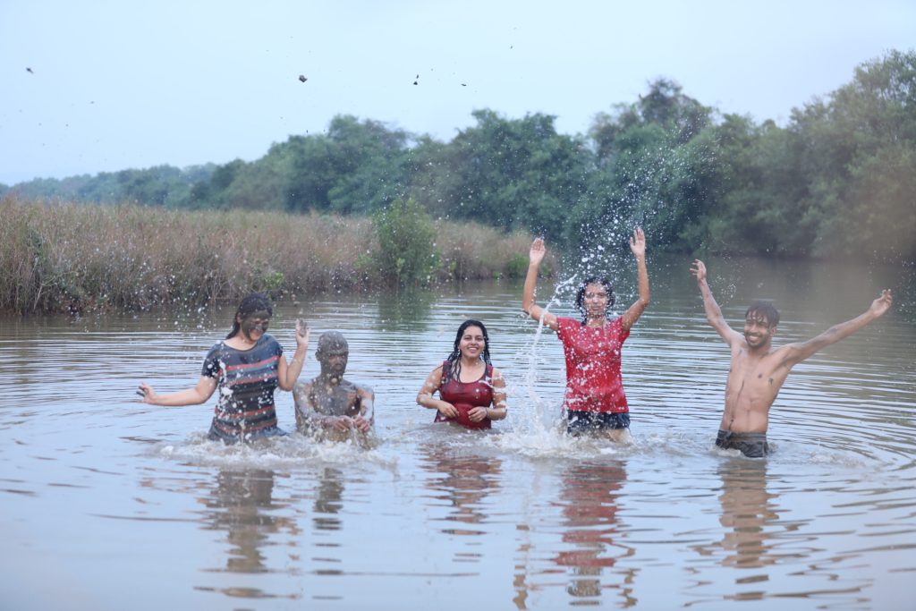 The image shows a group of friend on a mud bath in goa