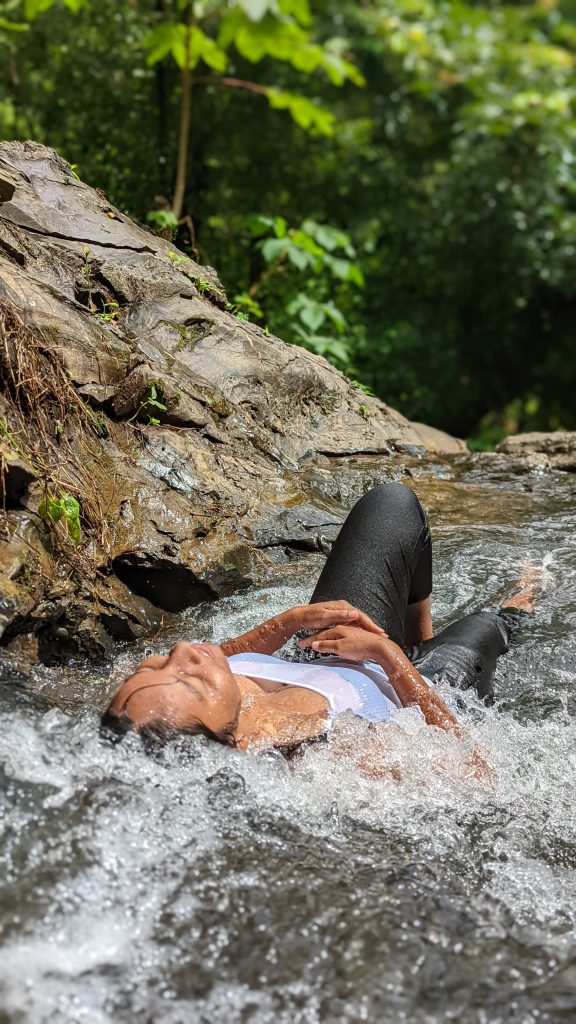 The image shows a traveller in Goa on a waterfall trek in Goa