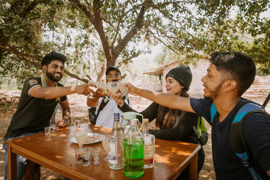 The image shows a group of friends on a feni tasting session in Goa