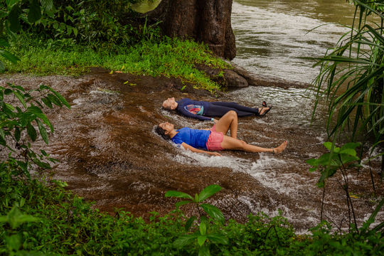 The image shows friend in goa on a vacation basking in a natural goan waterfall